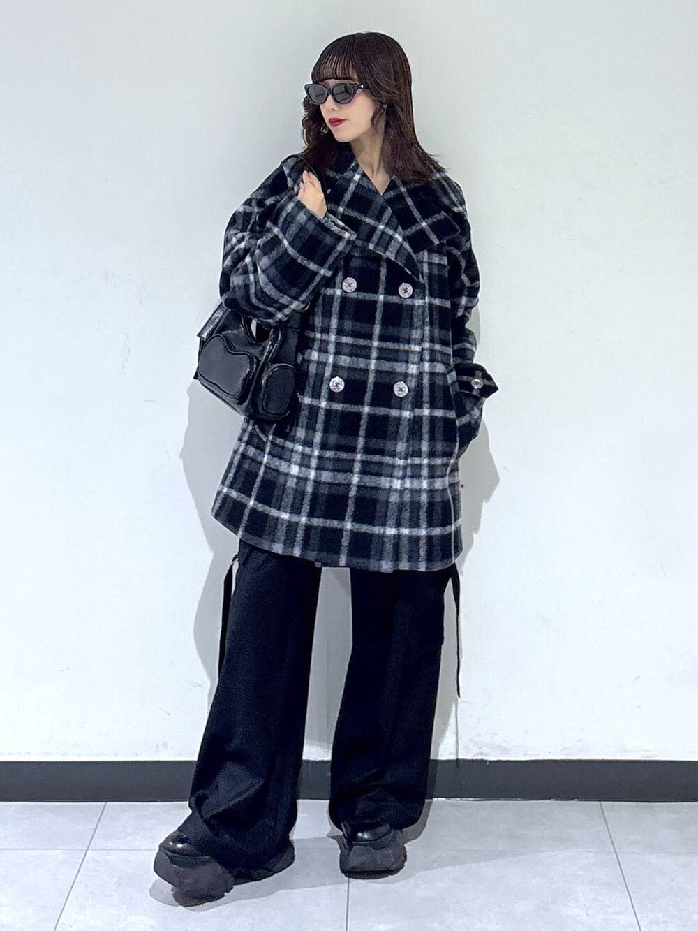 ブラック系のブーツ、ブラック系のチェスターコート、ブラック系のスラックスを着用したレディースの冬コーディネートの2枚目の写真