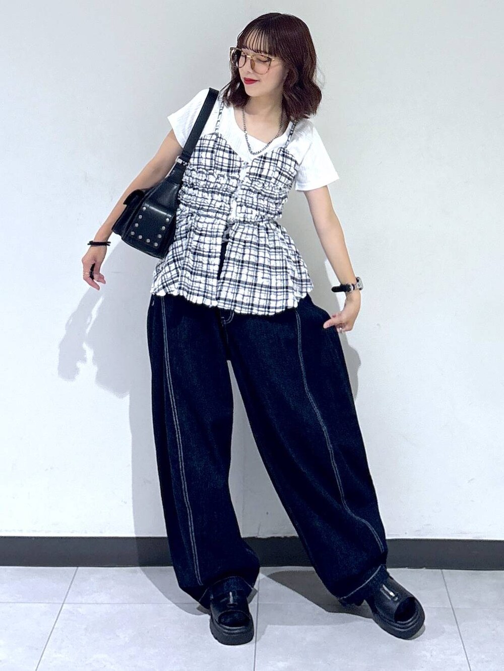 ブラック系のサンダル、ブルー系のデニムパンツ、ブラック系のショルダーバッグを着用したレディースの夏コーディネートの2枚目の写真