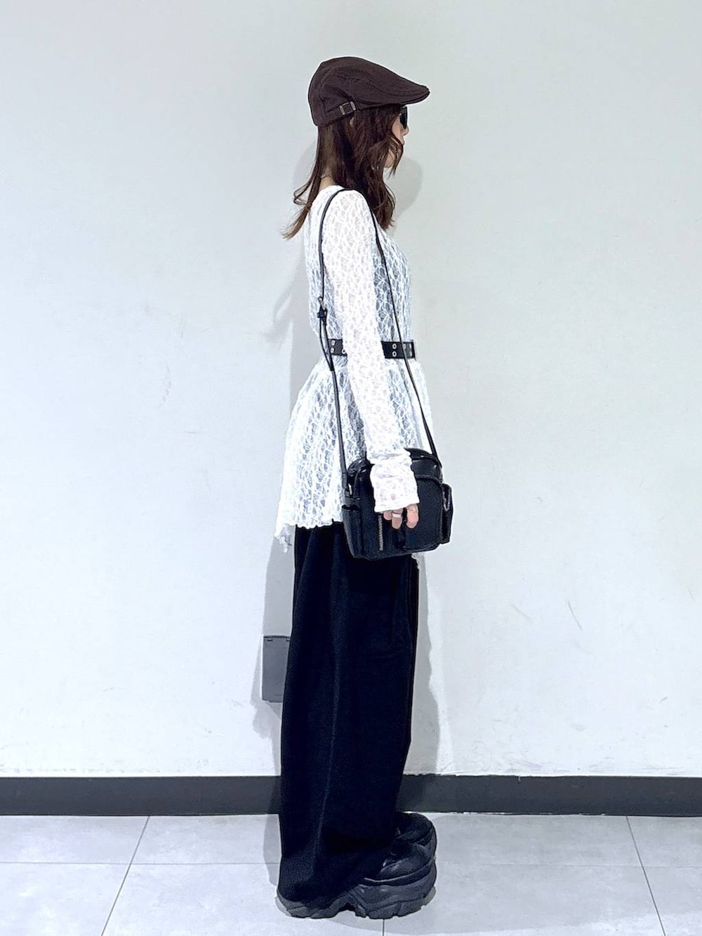 ブラック系のブーツ、ホワイト系のチュニック、ブラック系のショルダーバッグを着用したレディースの春コーディネートの3枚目の写真