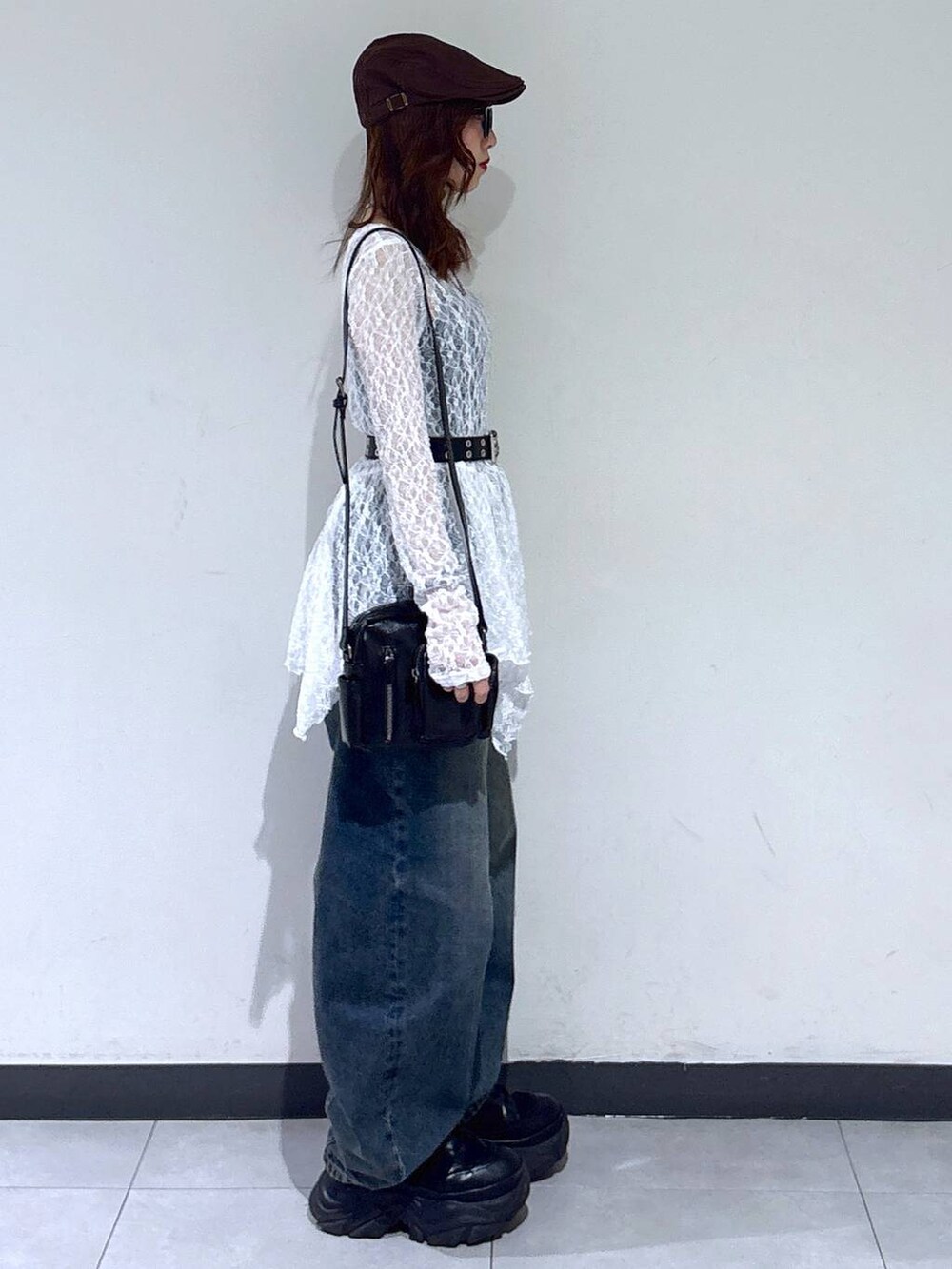 ブラック系のブーツ、ホワイト系のチュニック、ブラック系のショルダーバッグを着用したレディースの春コーディネートの3枚目の写真