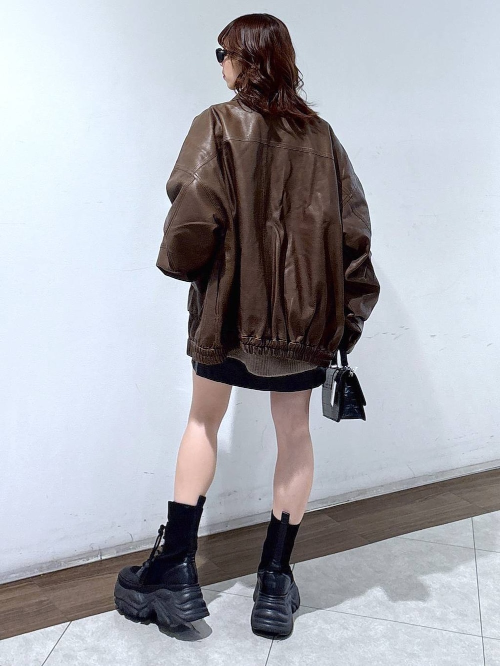 ブラック系のブーツ、ブラック系のハンドバッグ、ブラウン系のブルゾンを着用したレディースの秋コーディネートの6枚目の写真