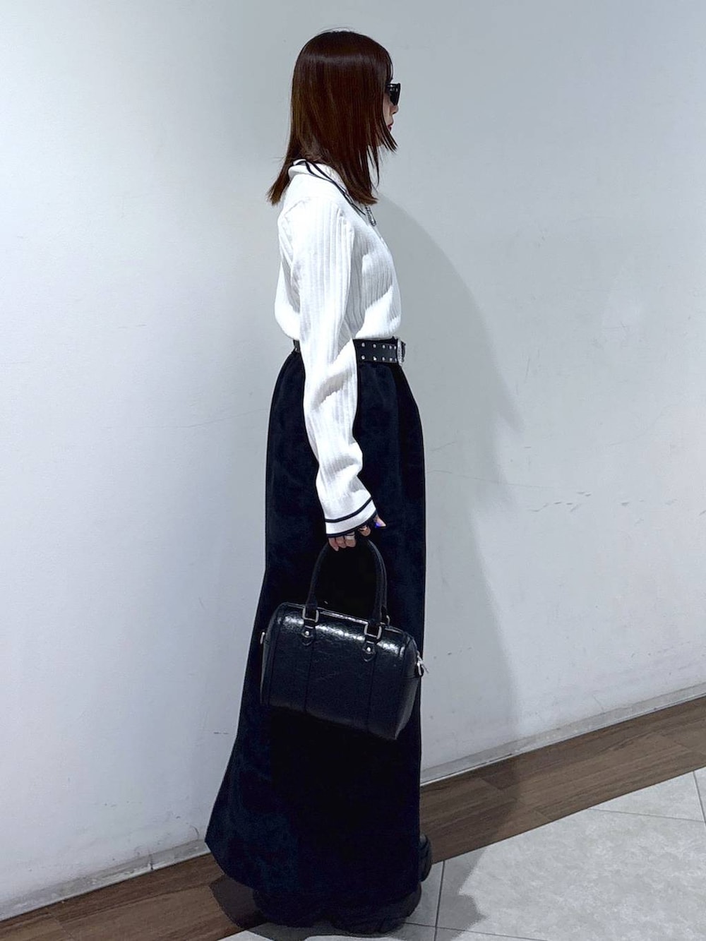 ブラック系のブーツ、ブラック系のスカート、ブラック系のボストンバッグを着用したレディースの春コーディネートの3枚目の写真