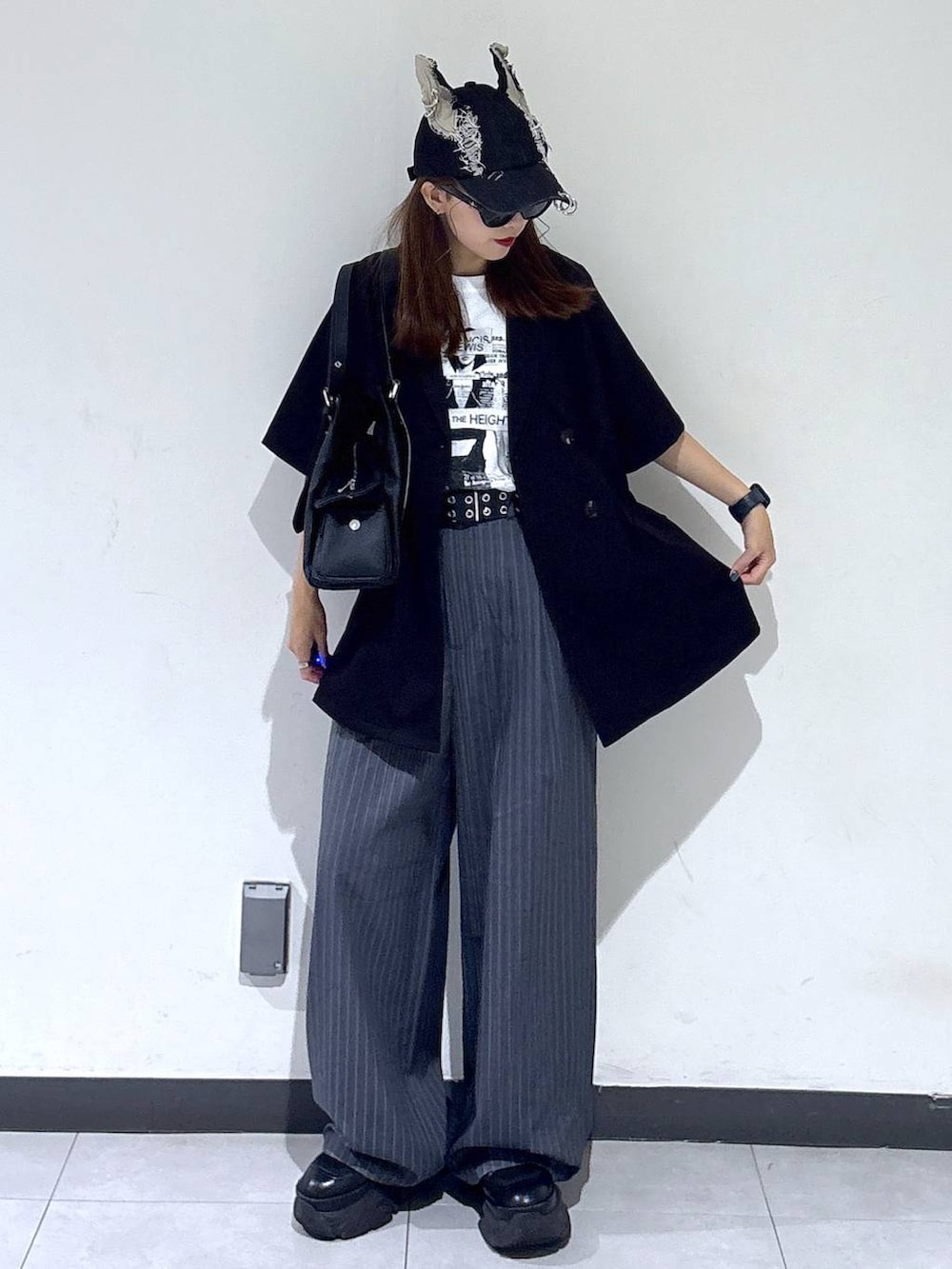 ホワイト系のTシャツ/カットソー、ブラック系のブーツ、ブラック系のハンドバッグを着用したレディースの夏コーディネートの2枚目の写真