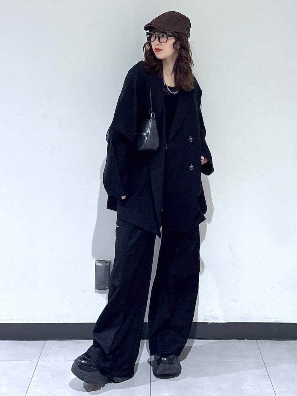 ブラック系のブーツ、ブラック系のハンドバッグ、ブラック系のスラックスを着用したレディースの春コーディネートの2枚目の写真