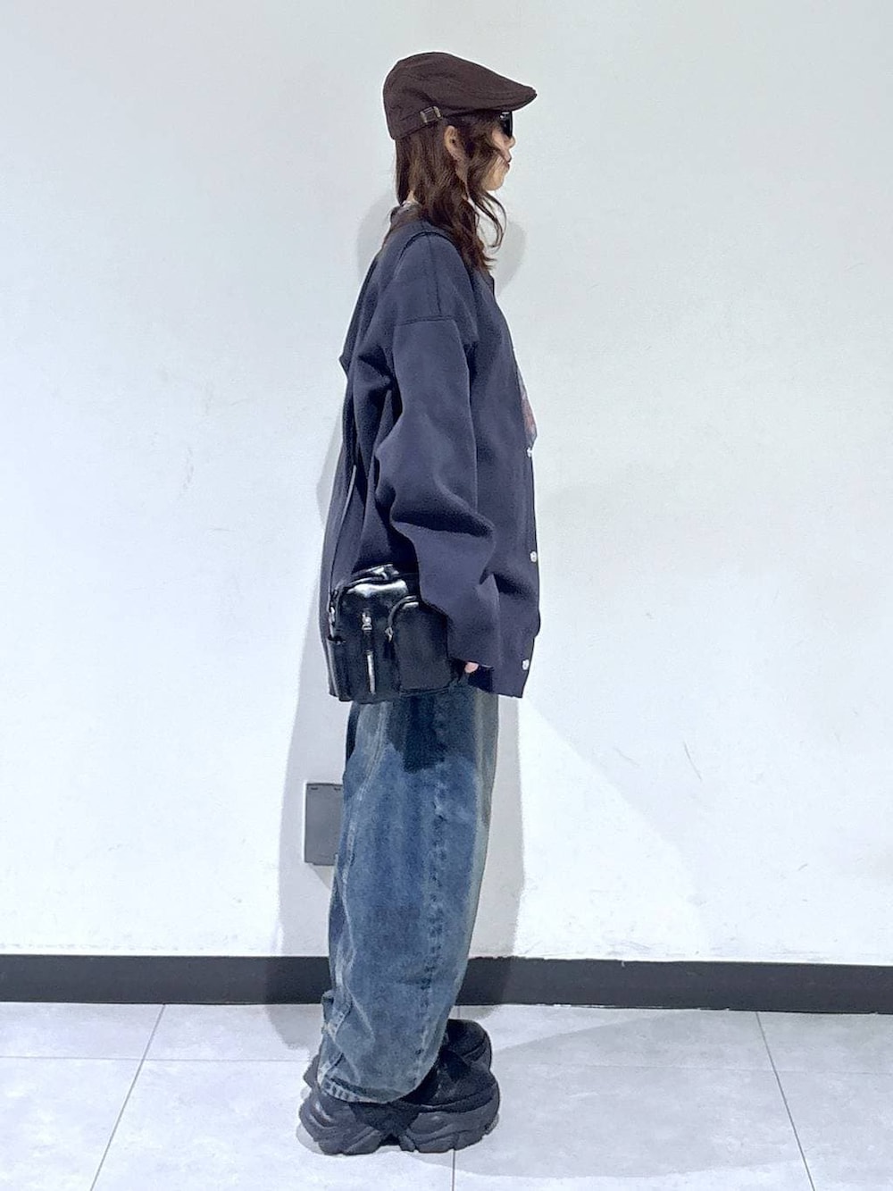 ブラック系のブーツ、ブルー系のデニムパンツ、ブラック系のショルダーバッグを着用したレディースの春コーディネートの3枚目の写真