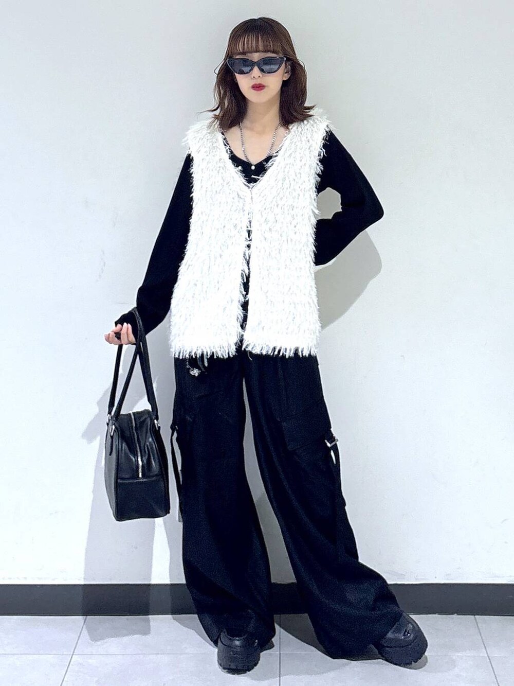 ホワイト系のベスト、ブラック系のTシャツ/カットソー、ブラック系のボストンバッグを着用したレディースの秋コーディネートの4枚目の写真