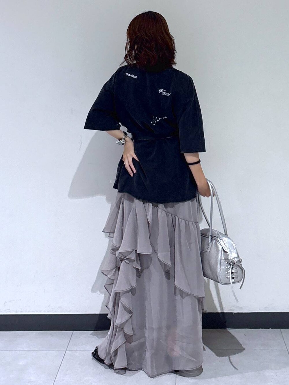 グレー系のスカート、シルバー系のショルダーバッグ、ブラック系のサンダルを着用したレディースの夏コーディネートの5枚目の写真