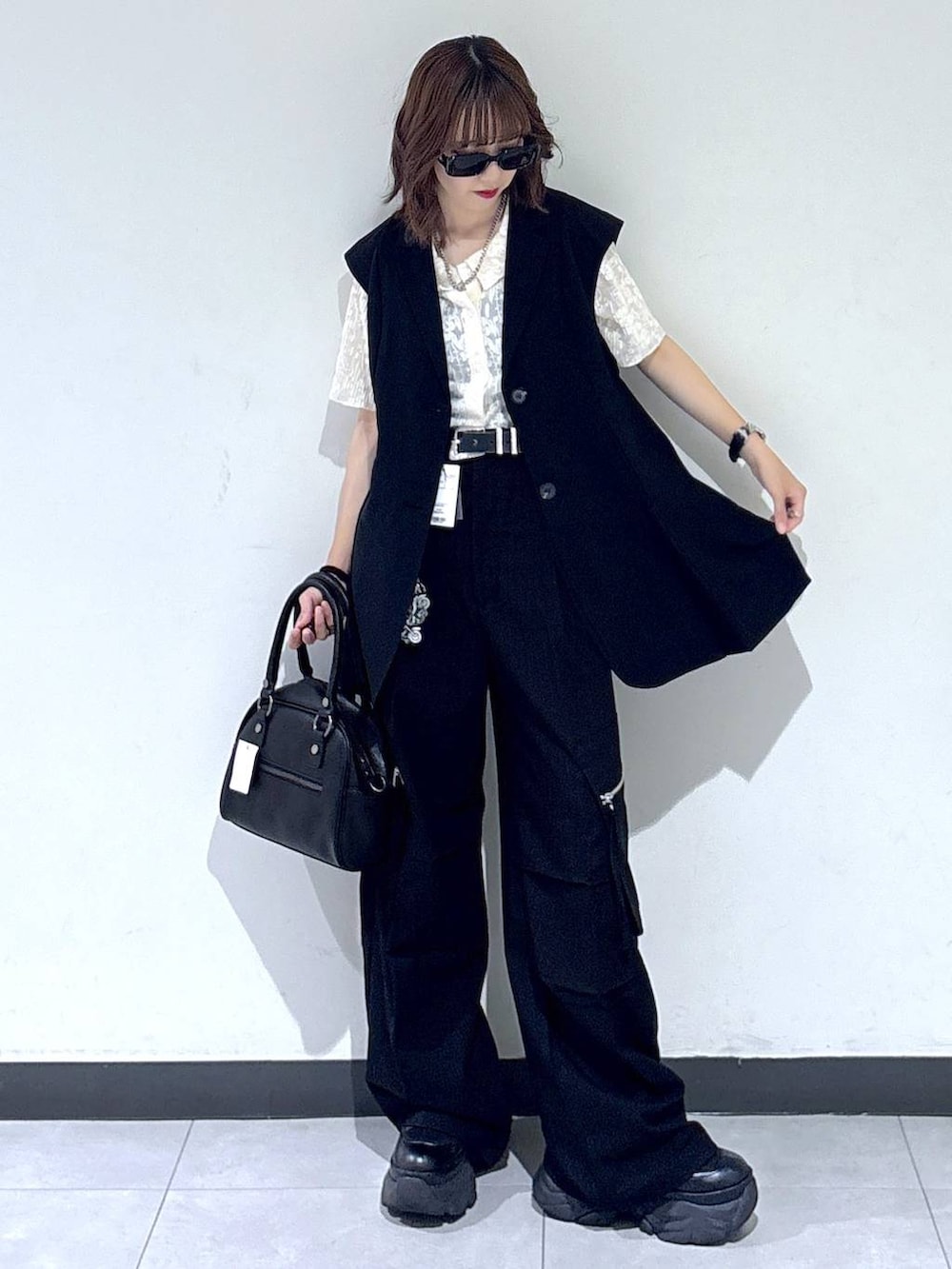 ブラック系のブーツ、ブラック系のカーゴパンツ、ブラック系のベストを着用したレディースの夏コーディネートの4枚目の写真