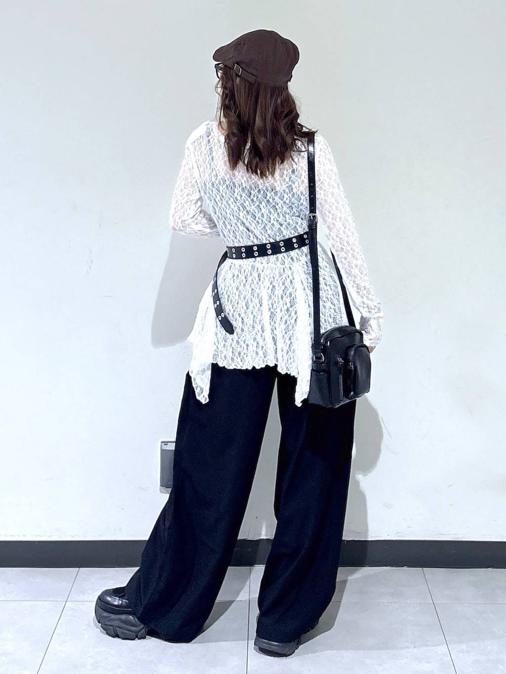 ブラック系のブーツ、ホワイト系のチュニック、ブラック系のショルダーバッグを着用したレディースの春コーディネートの6枚目の写真