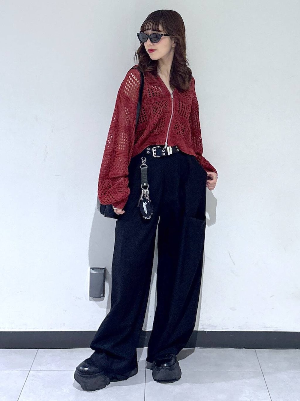 ブラック系のブーツ、ブラック系のショルダーバッグ、レッド系のパーカーを着用したレディースの春コーディネートの2枚目の写真