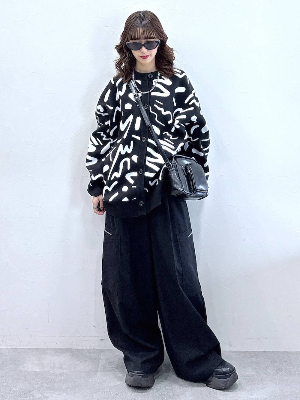 ブラック系のブーツ、ホワイト系のカーディガン/ボレロ、ブラック系のスラックスを着用したレディースの冬コーディネートの4枚目の写真