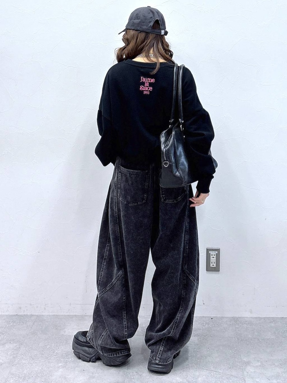 ブラック系のブーツ、ブラック系のボストンバッグ、ブラック系のデニムパンツを着用したレディースの冬コーディネートの3枚目の写真