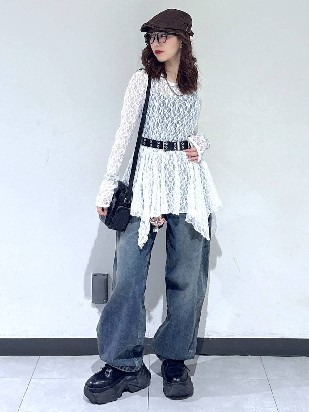 ブラック系のブーツ、ホワイト系のチュニック、ブラック系のショルダーバッグを着用したレディースの春コーディネートの4枚目の写真