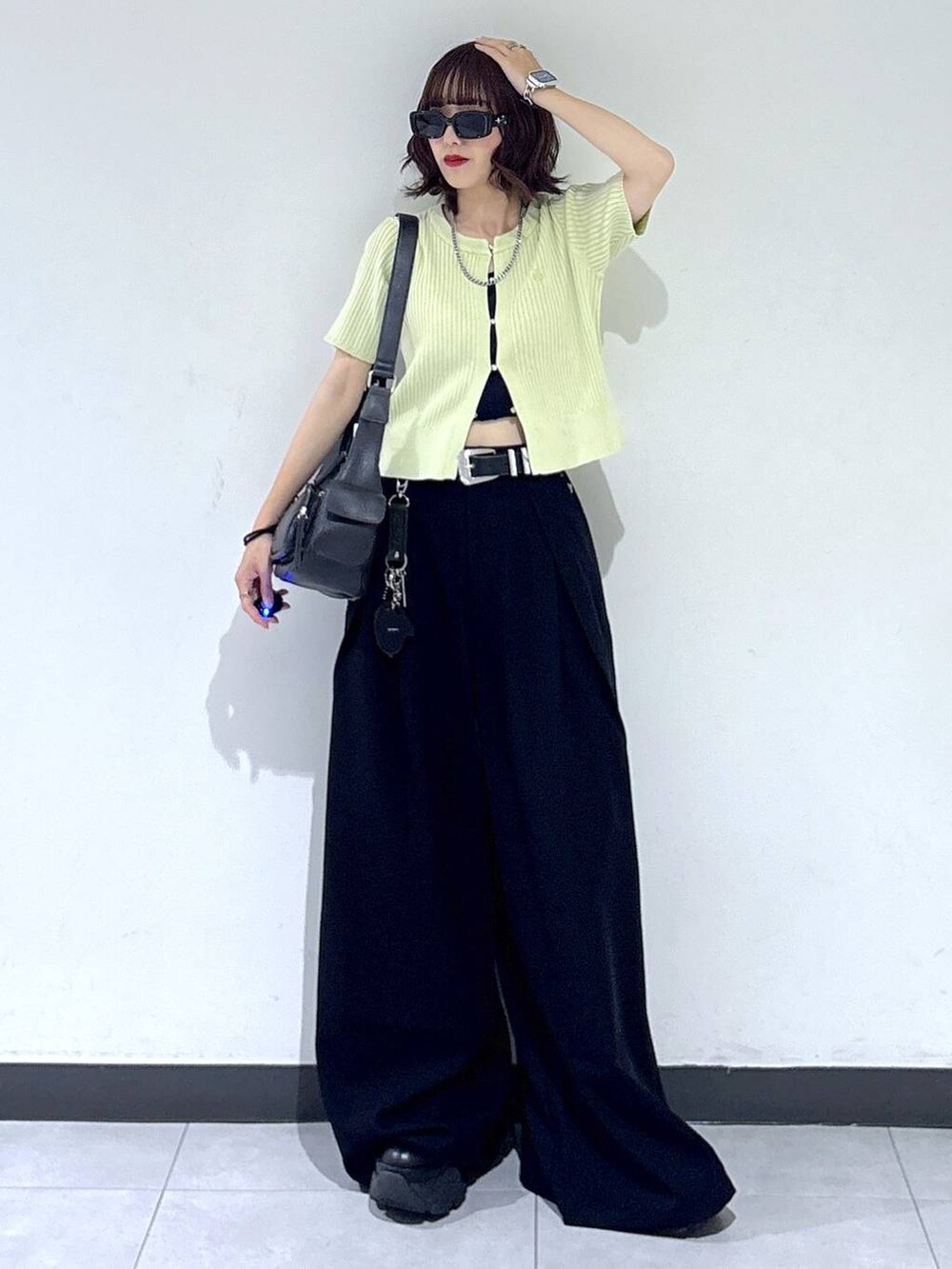 ブラック系のブーツ、ブラック系のスラックス、ブラック系のショルダーバッグを着用したレディースの夏コーディネートの3枚目の写真