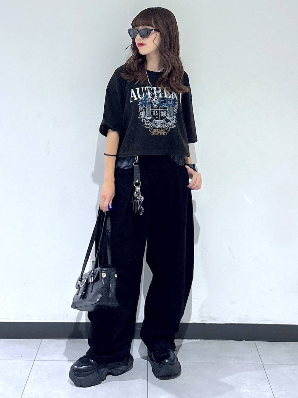 ブラック系のスラックス、グレー系のTシャツ/カットソー、ブラック系のブーツを着用したレディースの夏コーディネートの3枚目の写真
