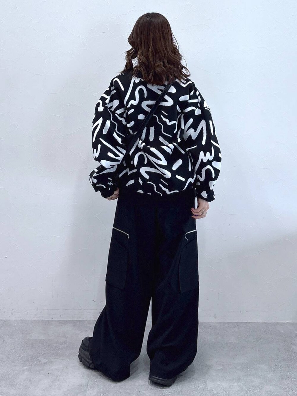 ブラック系のブーツ、ホワイト系のカーディガン/ボレロ、ブラック系のスラックスを着用したレディースの冬コーディネートの5枚目の写真