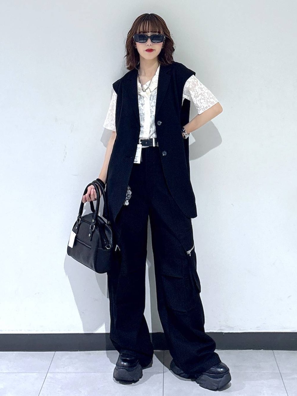 ブラック系のブーツ、ブラック系のカーゴパンツ、ブラック系のベストを着用したレディースの夏コーディネートの5枚目の写真