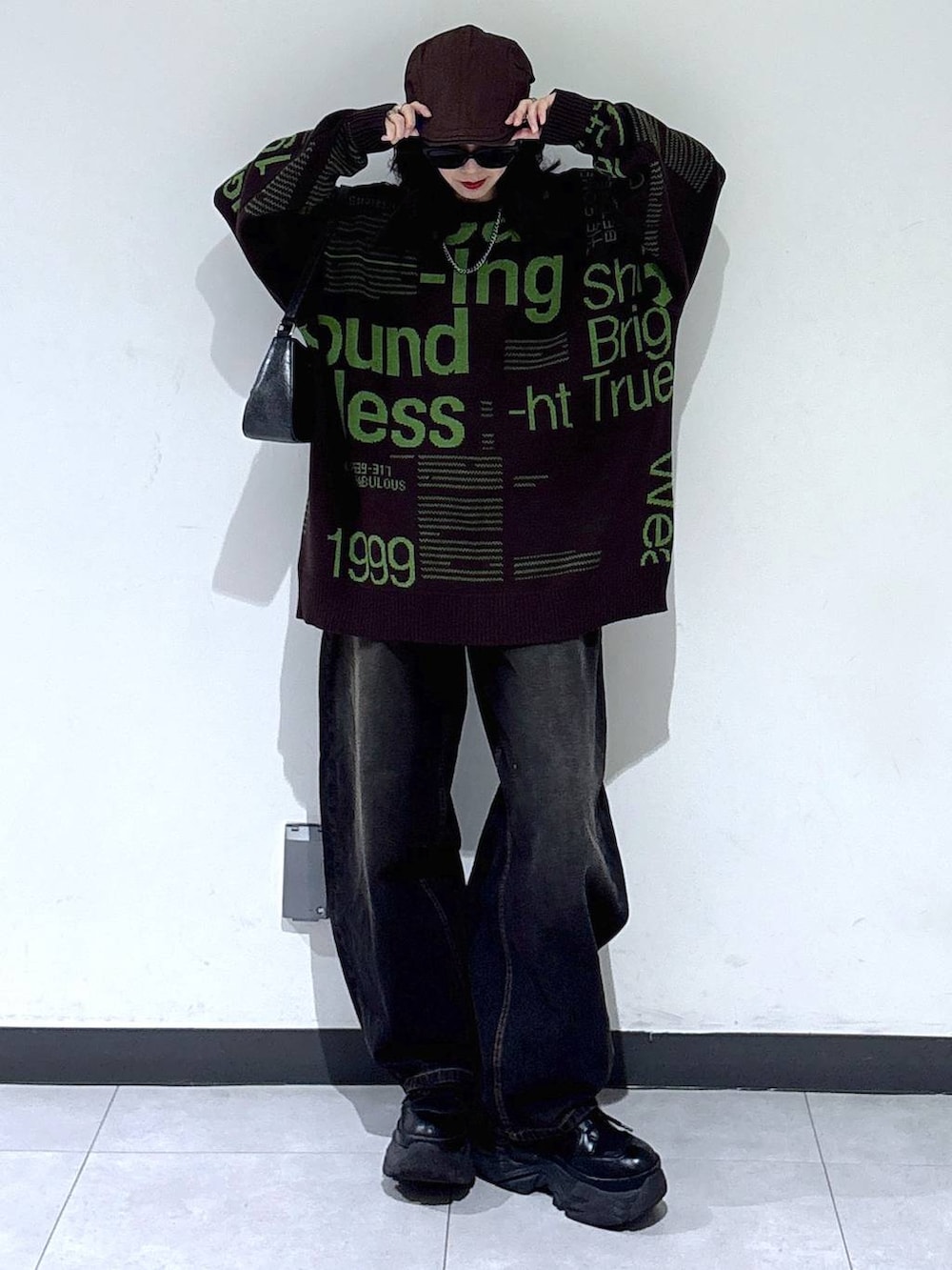 ブラック系のブーツ、ブラック系のデニムパンツ、ブラウン系のニット/セーターを着用したレディースの冬コーディネートの4枚目の写真