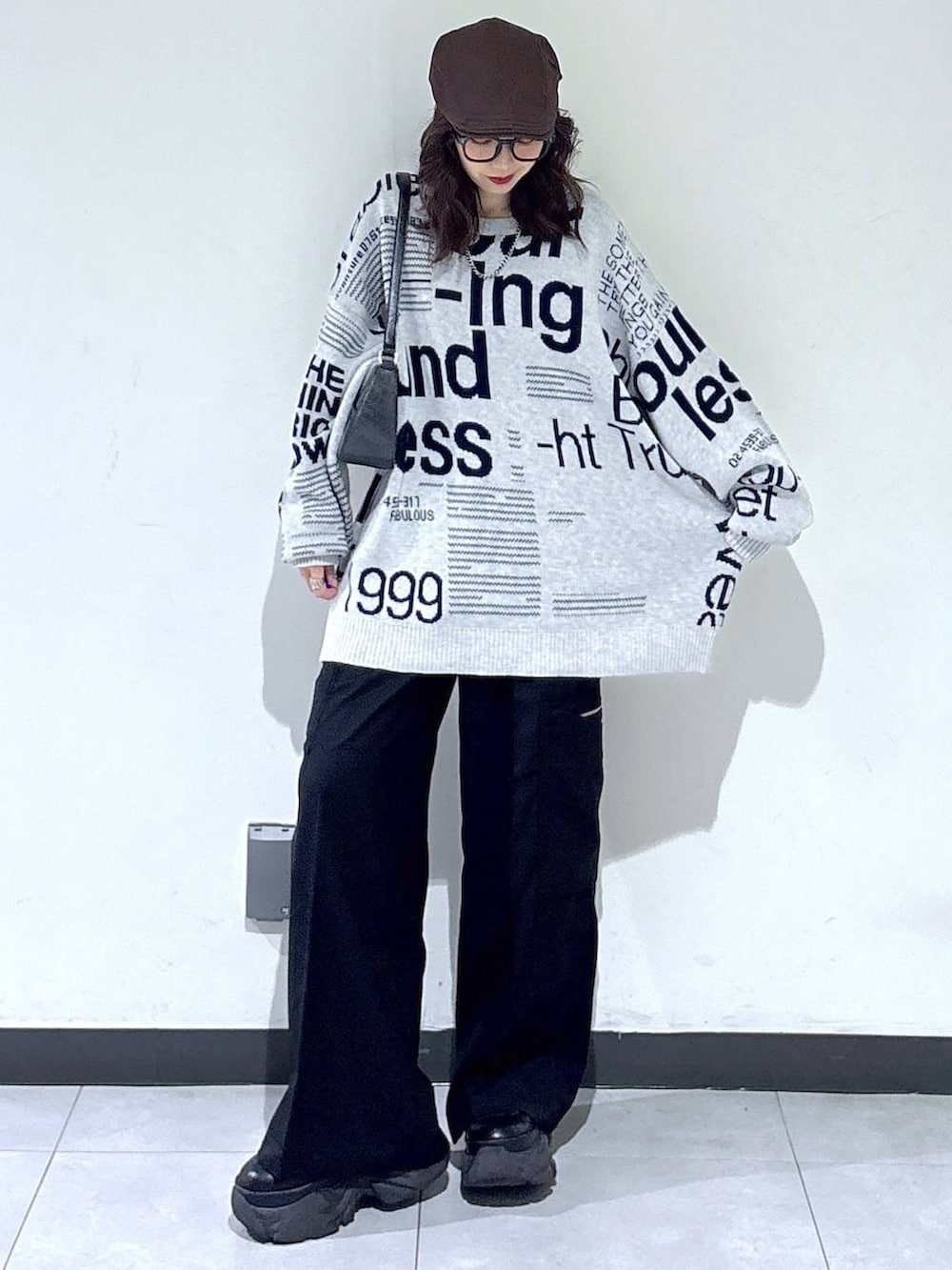 ブラック系のブーツ、ブラック系のハンドバッグ、グレー系のニット/セーターを着用したレディースの春コーディネートの2枚目の写真