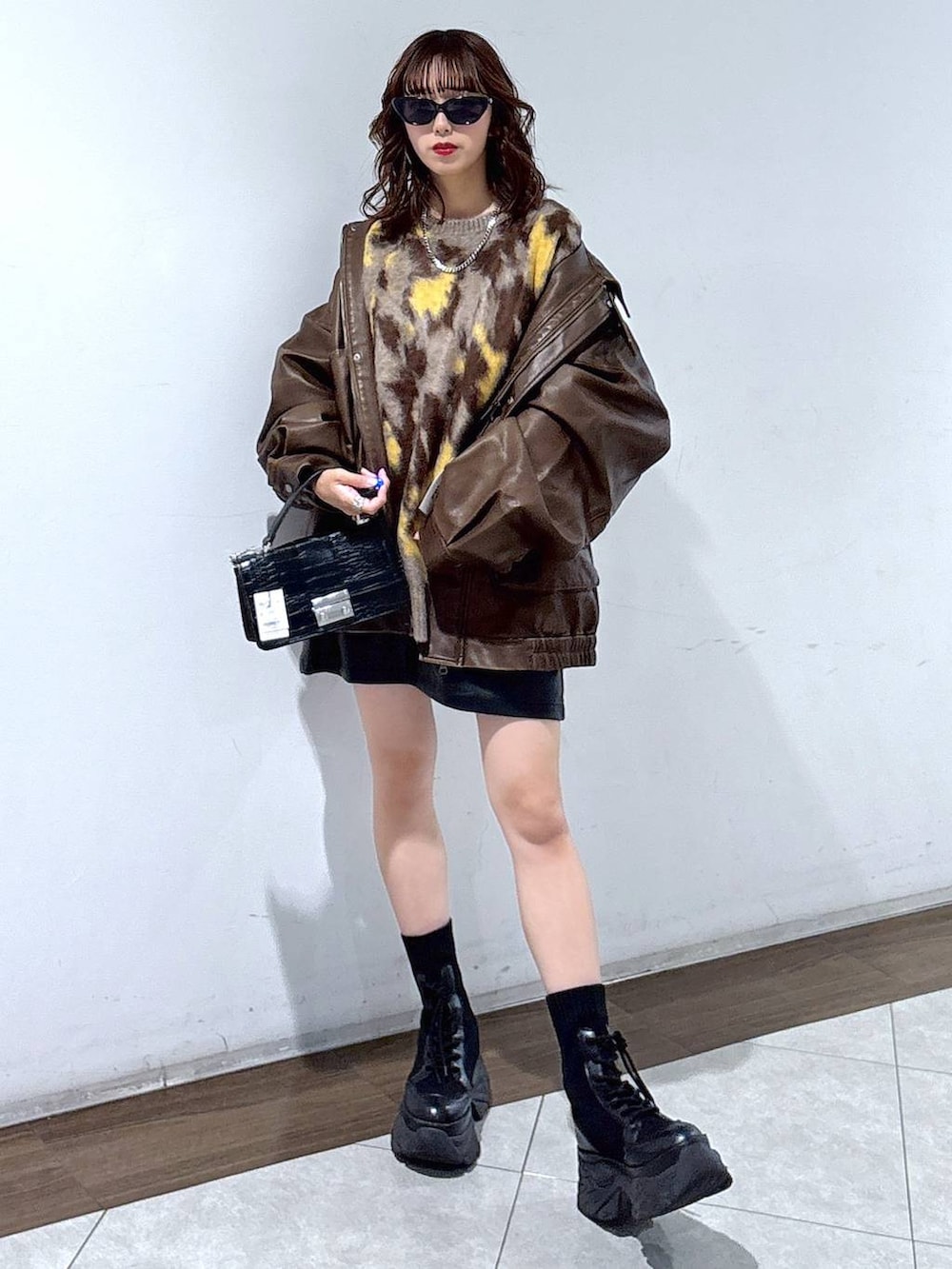 ブラック系のブーツ、ブラック系のハンドバッグ、ブラウン系のブルゾンを着用したレディースの秋コーディネートの5枚目の写真