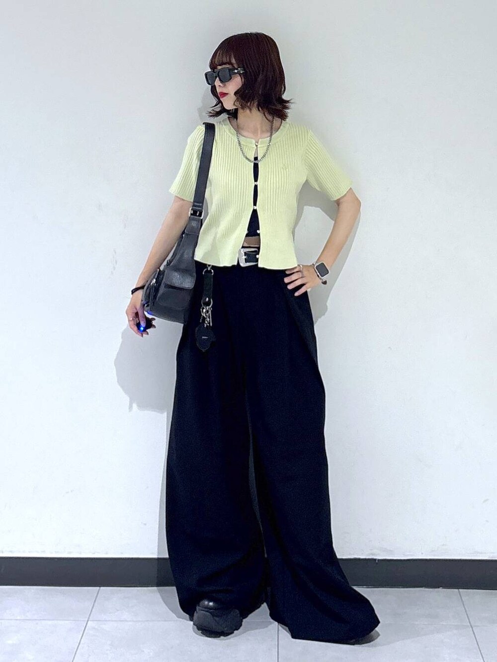 ブラック系のブーツ、ブラック系のスラックス、ブラック系のショルダーバッグを着用したレディースの夏コーディネートの4枚目の写真