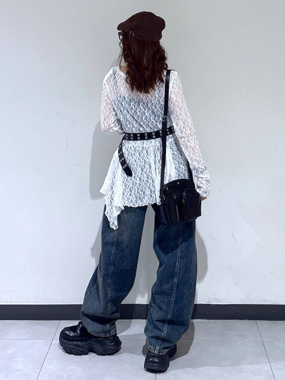 ブラック系のブーツ、ホワイト系のチュニック、ブラック系のショルダーバッグを着用したレディースの春コーディネートの5枚目の写真