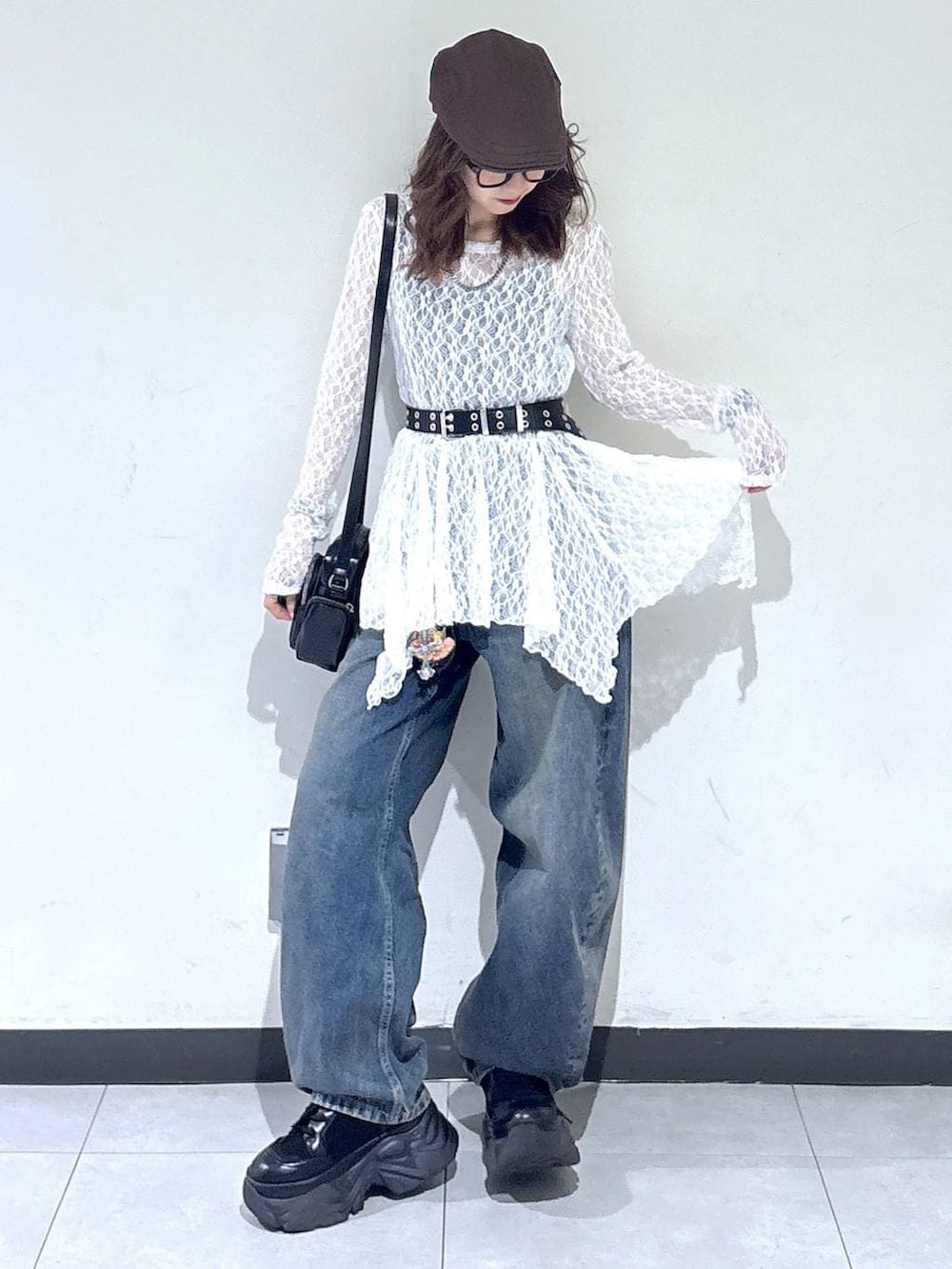 ブラック系のブーツ、ホワイト系のチュニック、ブラック系のショルダーバッグを着用したレディースの春コーディネートの2枚目の写真