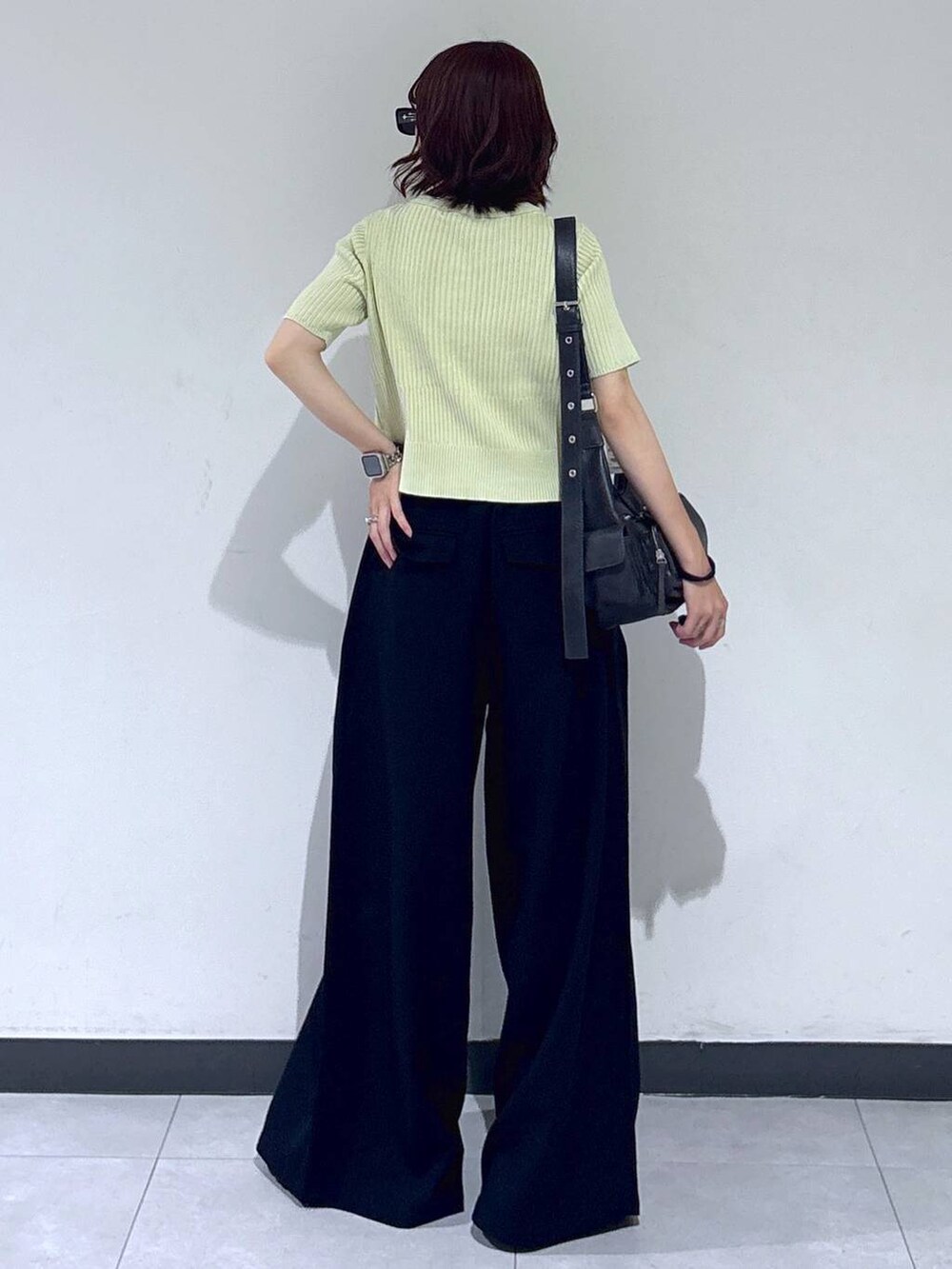 ブラック系のブーツ、ブラック系のスラックス、ブラック系のショルダーバッグを着用したレディースの夏コーディネートの6枚目の写真