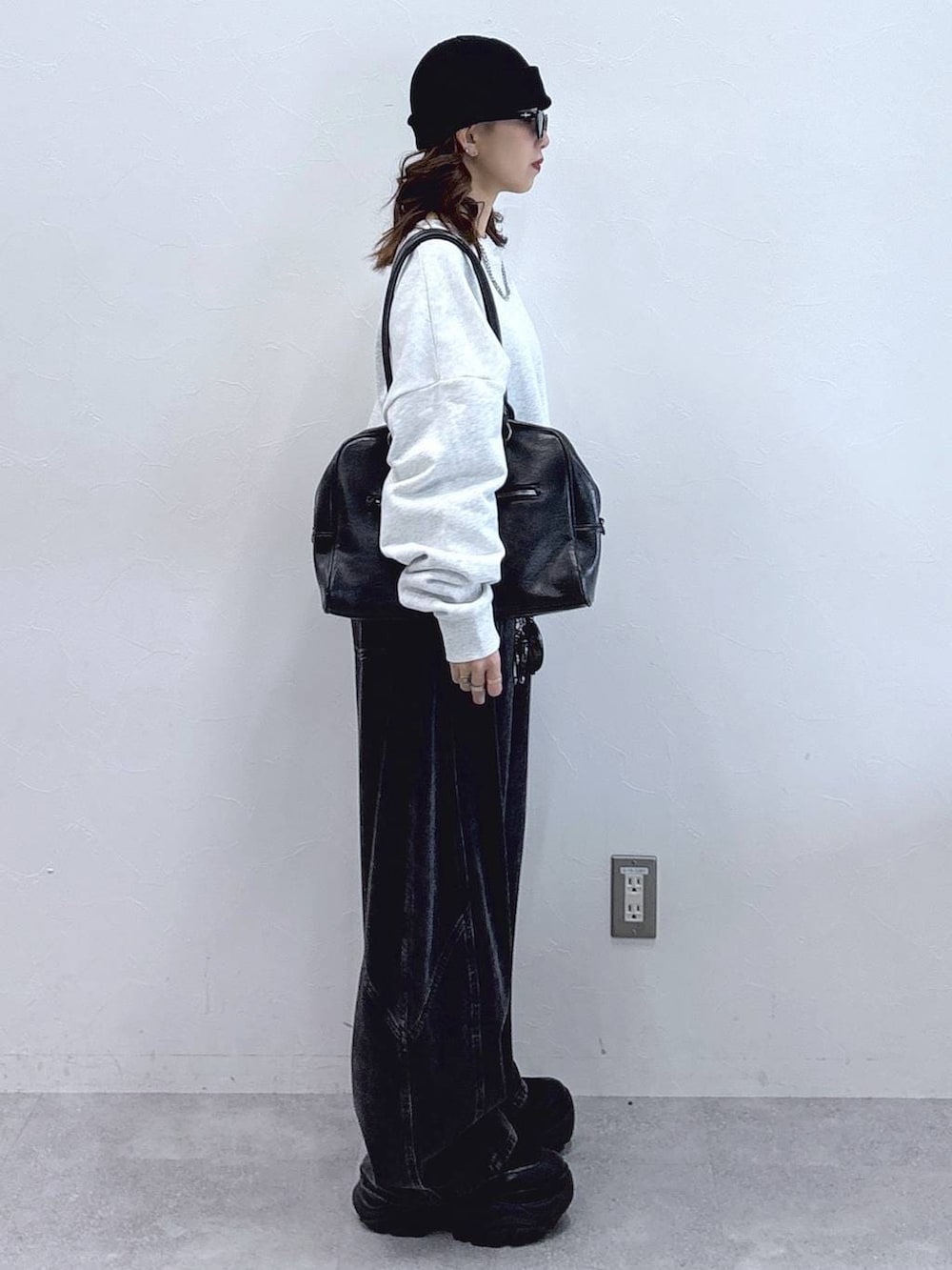 ブラック系のブーツ、ブラック系のボストンバッグ、ブラック系のデニムパンツを着用したレディースの冬コーディネートの5枚目の写真