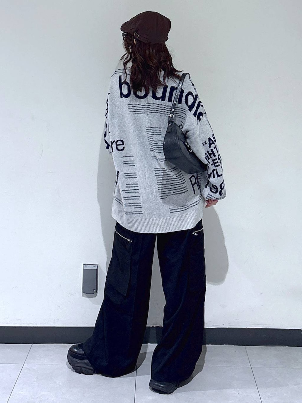 ブラック系のブーツ、ブラック系のハンドバッグ、グレー系のニット/セーターを着用したレディースの春コーディネートの7枚目の写真