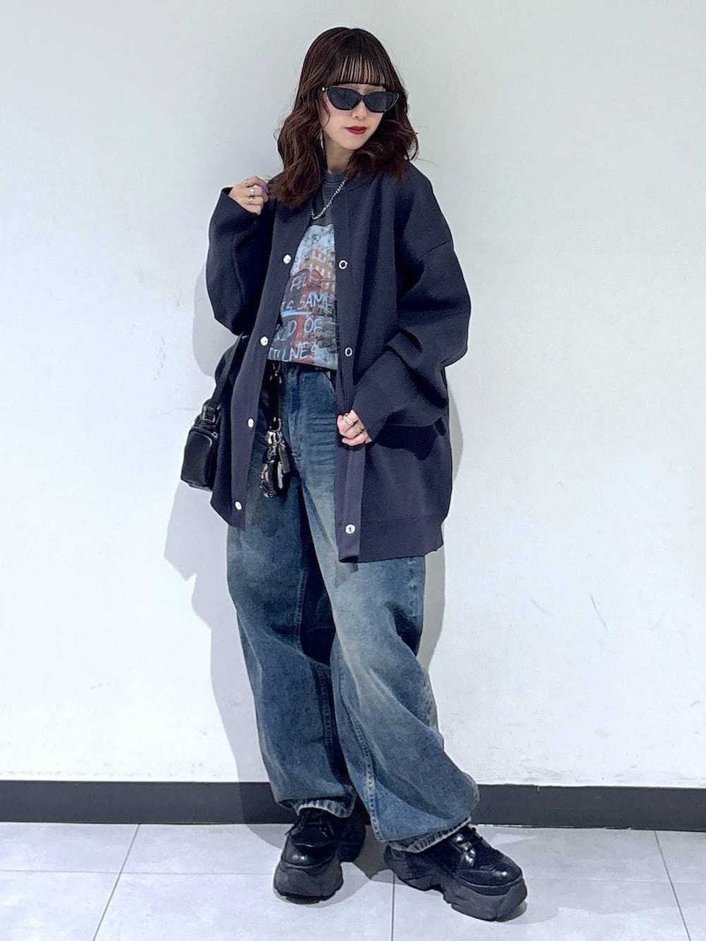 ブラック系のブーツ、ブルー系のデニムパンツ、ブラック系のショルダーバッグを着用したレディースの春コーディネートの4枚目の写真