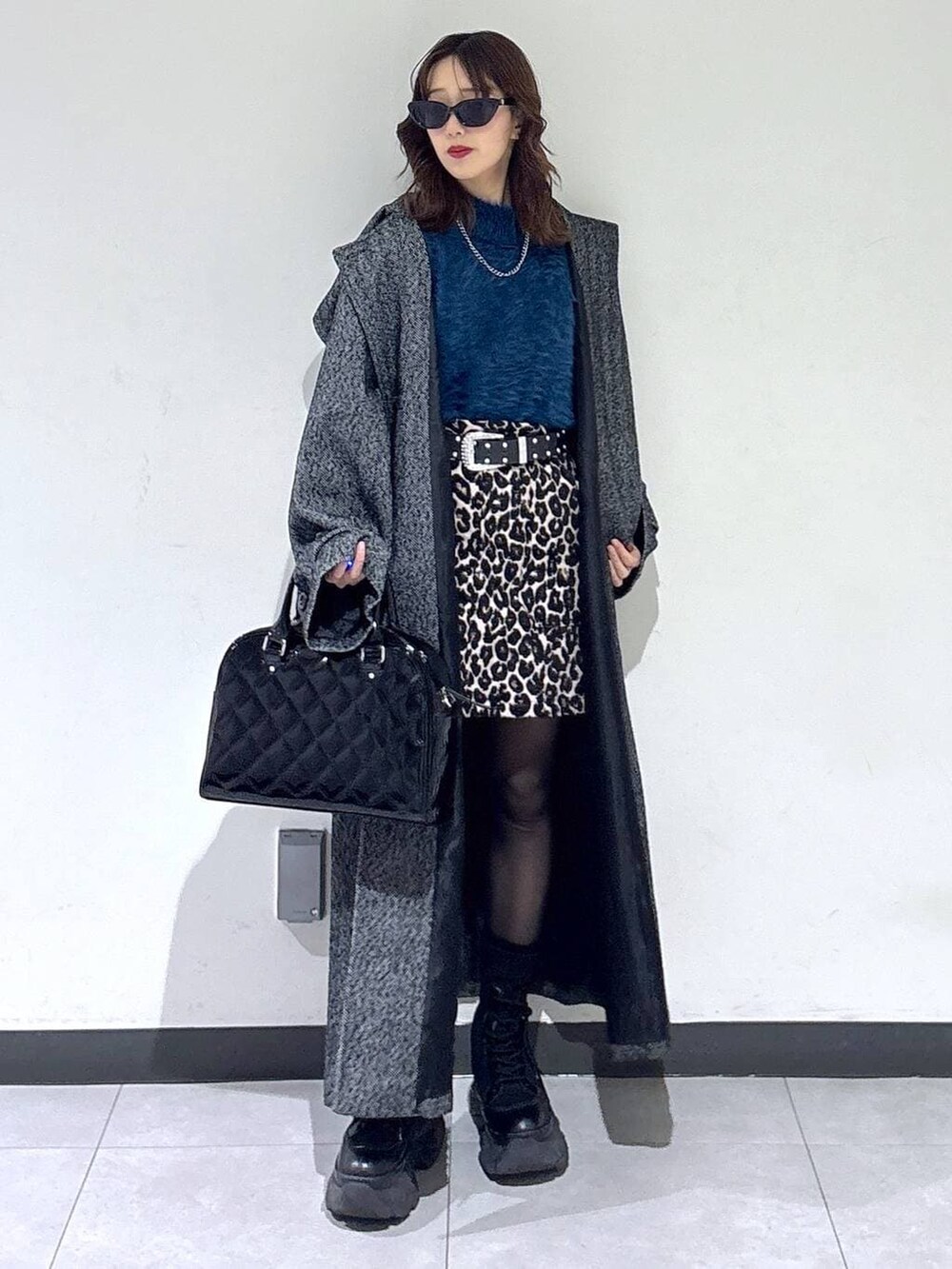 ブラック系のブーツ、ブラック系のチェスターコート、ブラウン系のスカートを着用したレディースの冬コーディネートの3枚目の写真