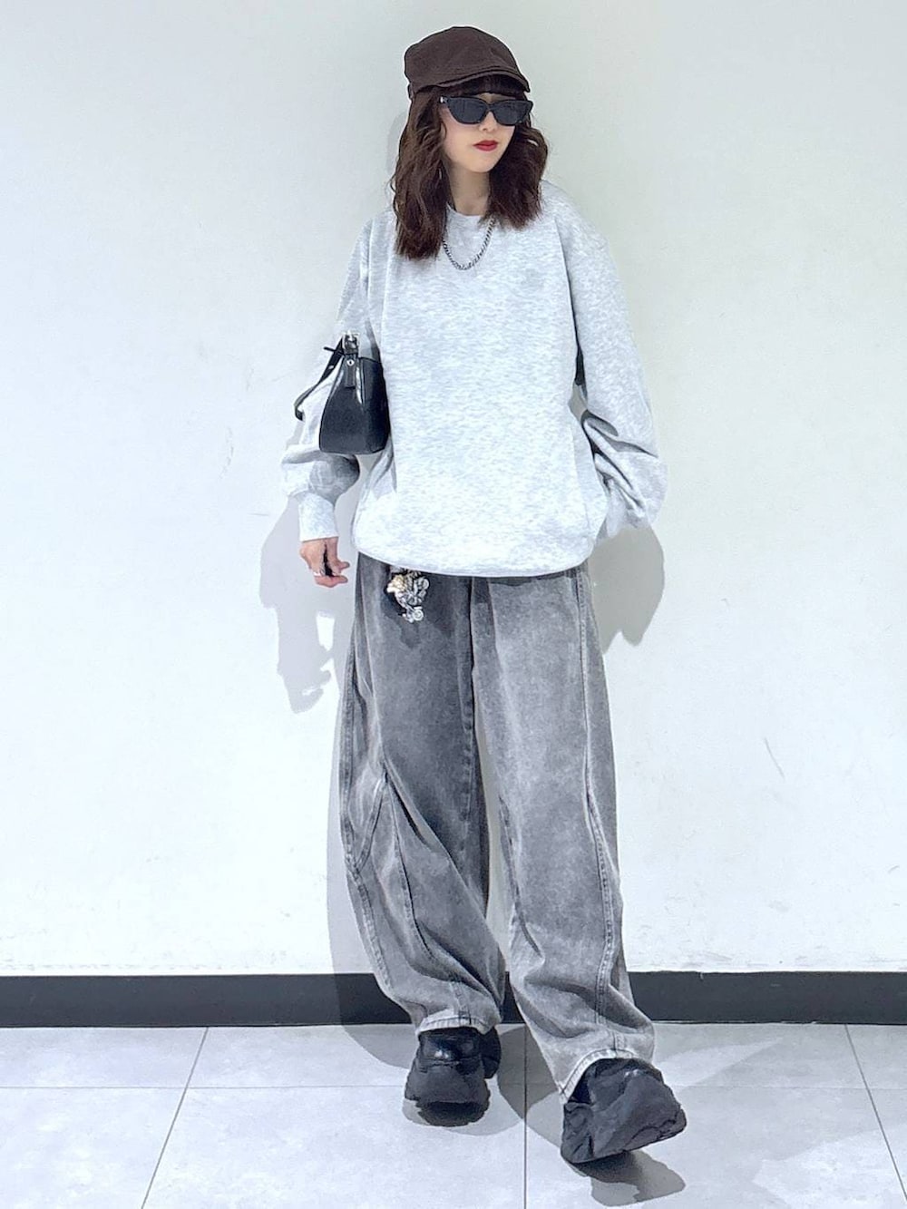 ブラック系のブーツ、グレー系のスウェット、ブラック系のハンドバッグを着用したレディースの春コーディネートの4枚目の写真