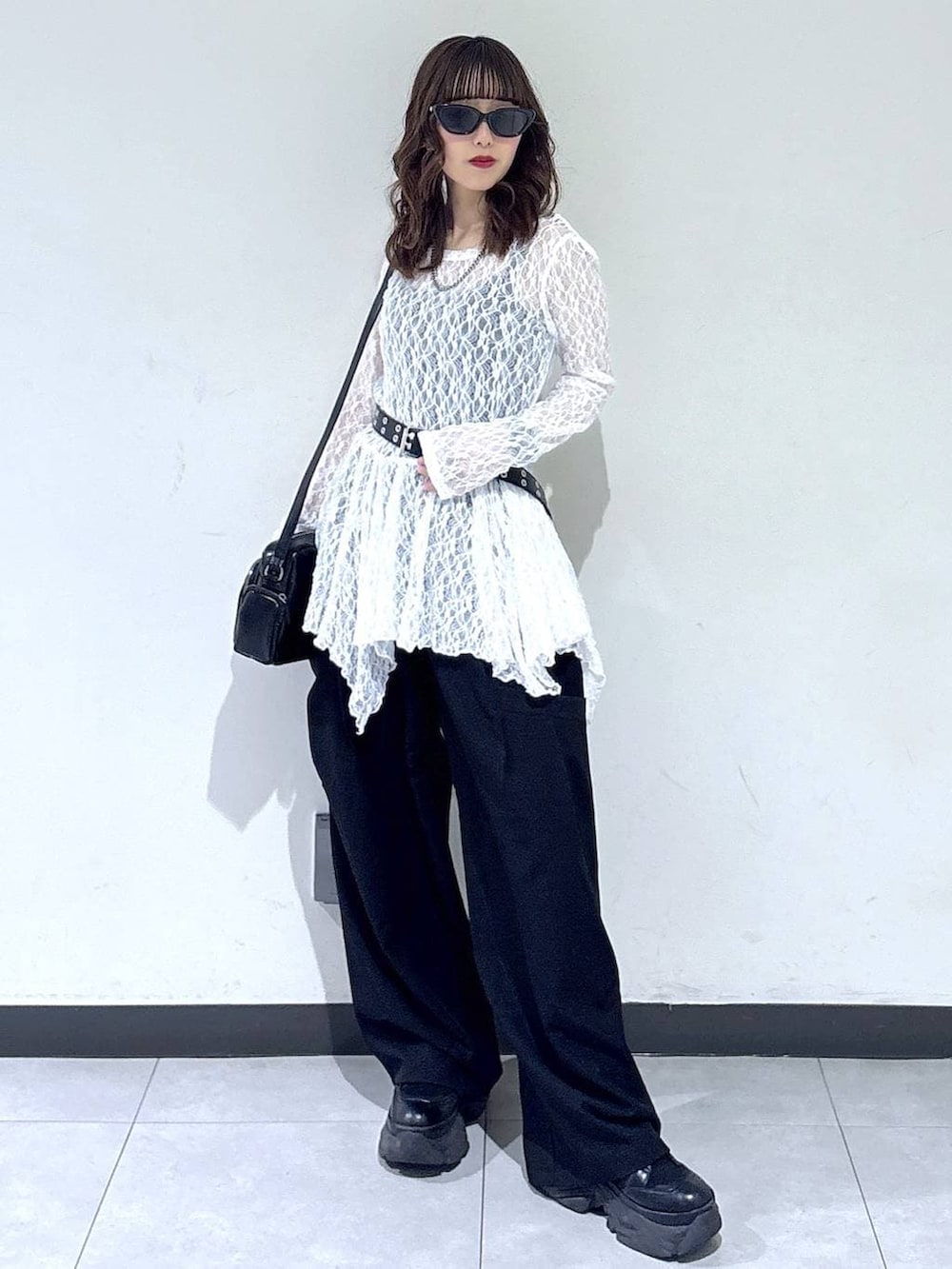 ブラック系のブーツ、ホワイト系のチュニック、ブラック系のショルダーバッグを着用したレディースの春コーディネートの4枚目の写真