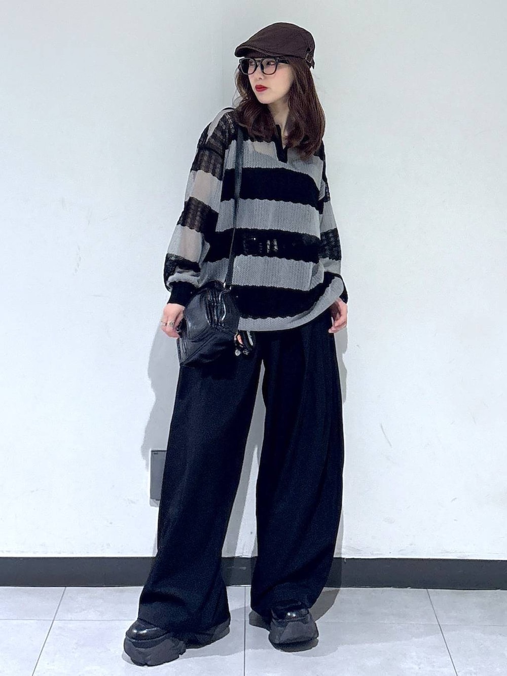 ブラック系のブーツ、ブラック系のスラックス、ブラック系のショルダーバッグを着用したレディースの春コーディネートの6枚目の写真