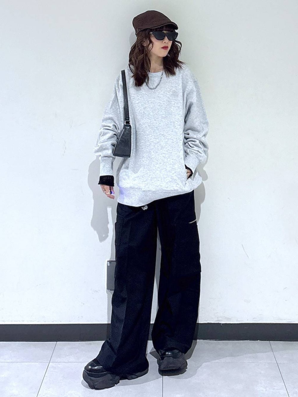 ブラック系のブーツ、グレー系のスウェット、ブラック系のスラックスを着用したレディースの春コーディネートの4枚目の写真