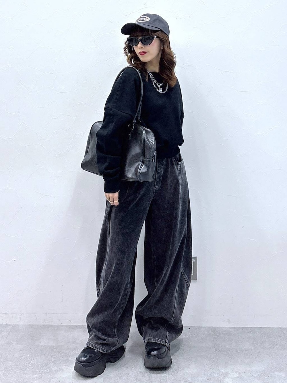 ブラック系のブーツ、ブラック系のボストンバッグ、ブラック系のデニムパンツを着用したレディースの冬コーディネートの4枚目の写真