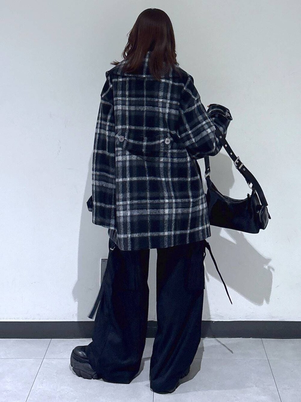 ブラック系のブーツ、ブラック系のチェスターコート、ブラック系のスラックスを着用したレディースの冬コーディネートの5枚目の写真