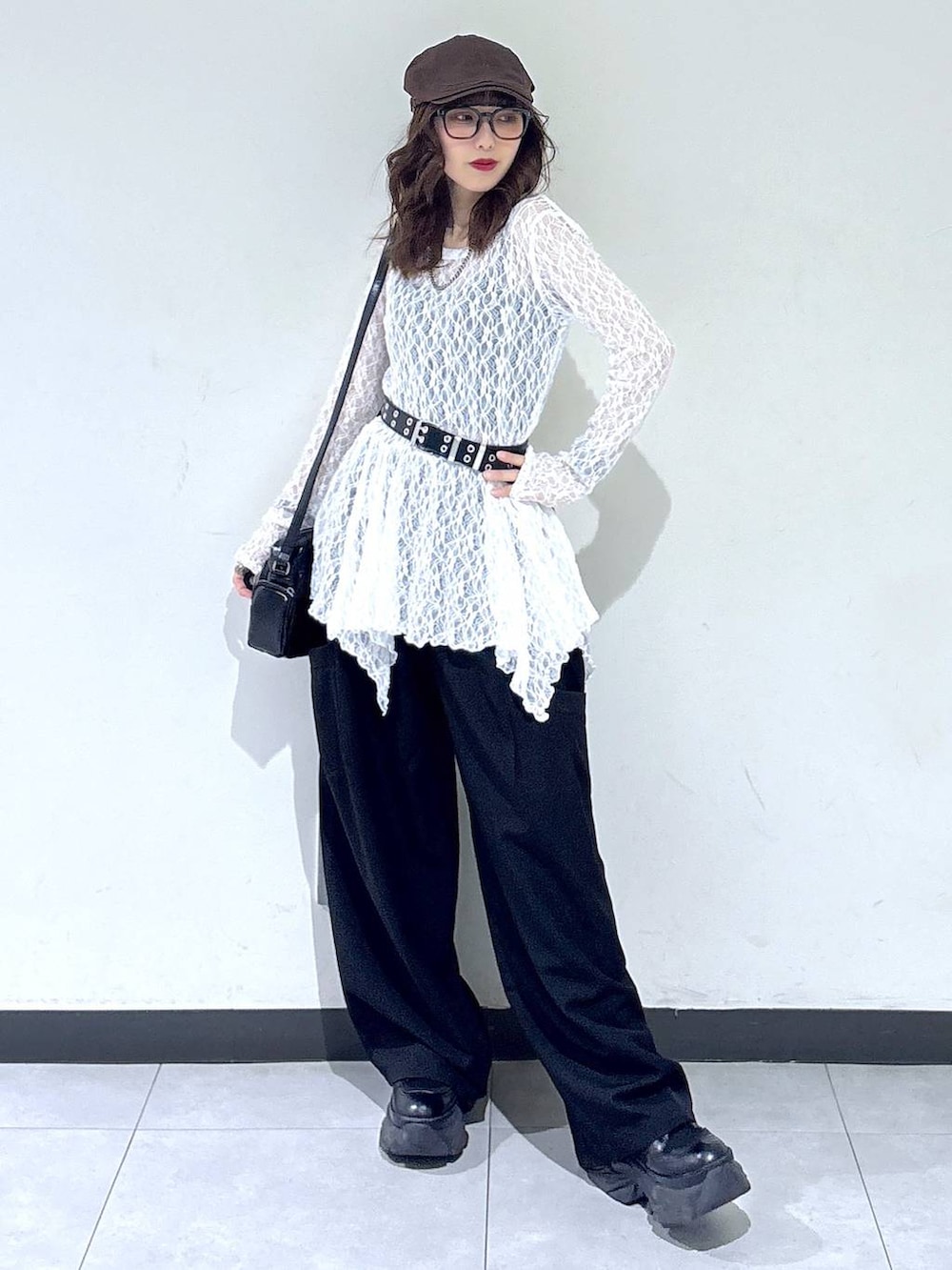 ブラック系のブーツ、ホワイト系のチュニック、ブラック系のショルダーバッグを着用したレディースの春コーディネートの2枚目の写真