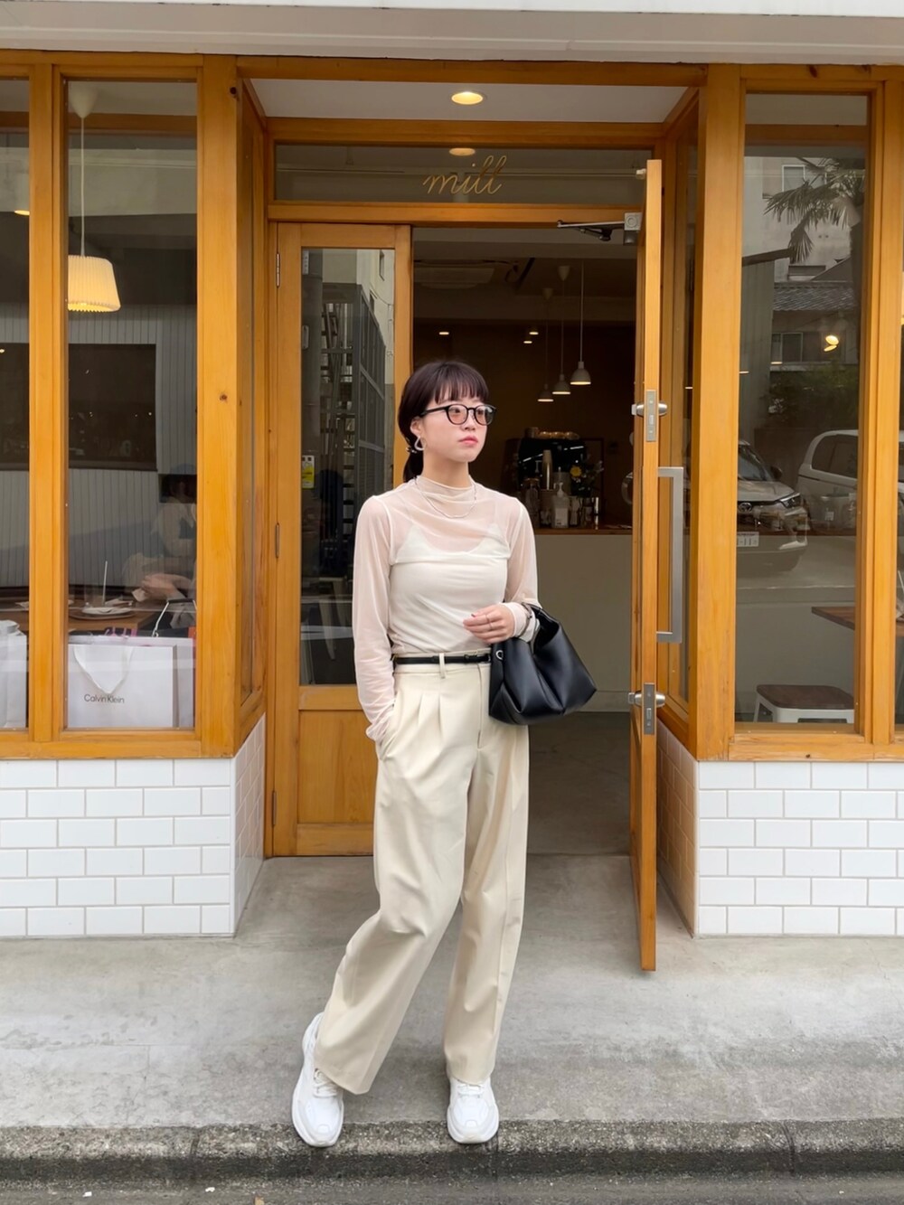 ホワイト系のTシャツ/カットソー、ブラック系のハンドバッグ、ホワイト系のスラックスを着用したレディースの春コーディネートの2枚目の写真