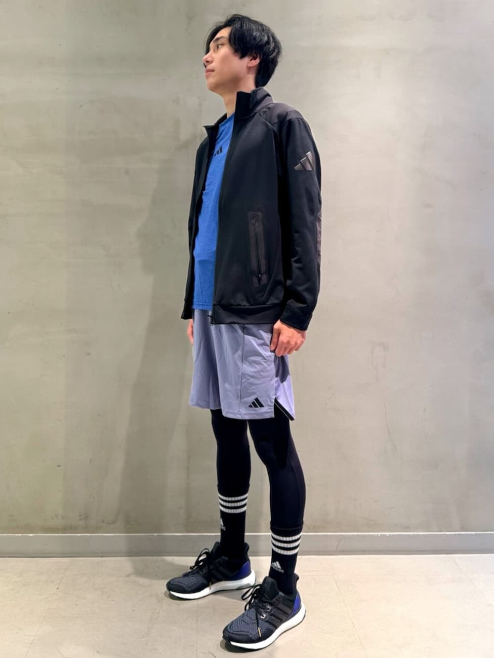 ブラック系のジャージ、ブルー系のトップス、ブラック系のスニーカーを着用したメンズの春コーディネートの2枚目の写真