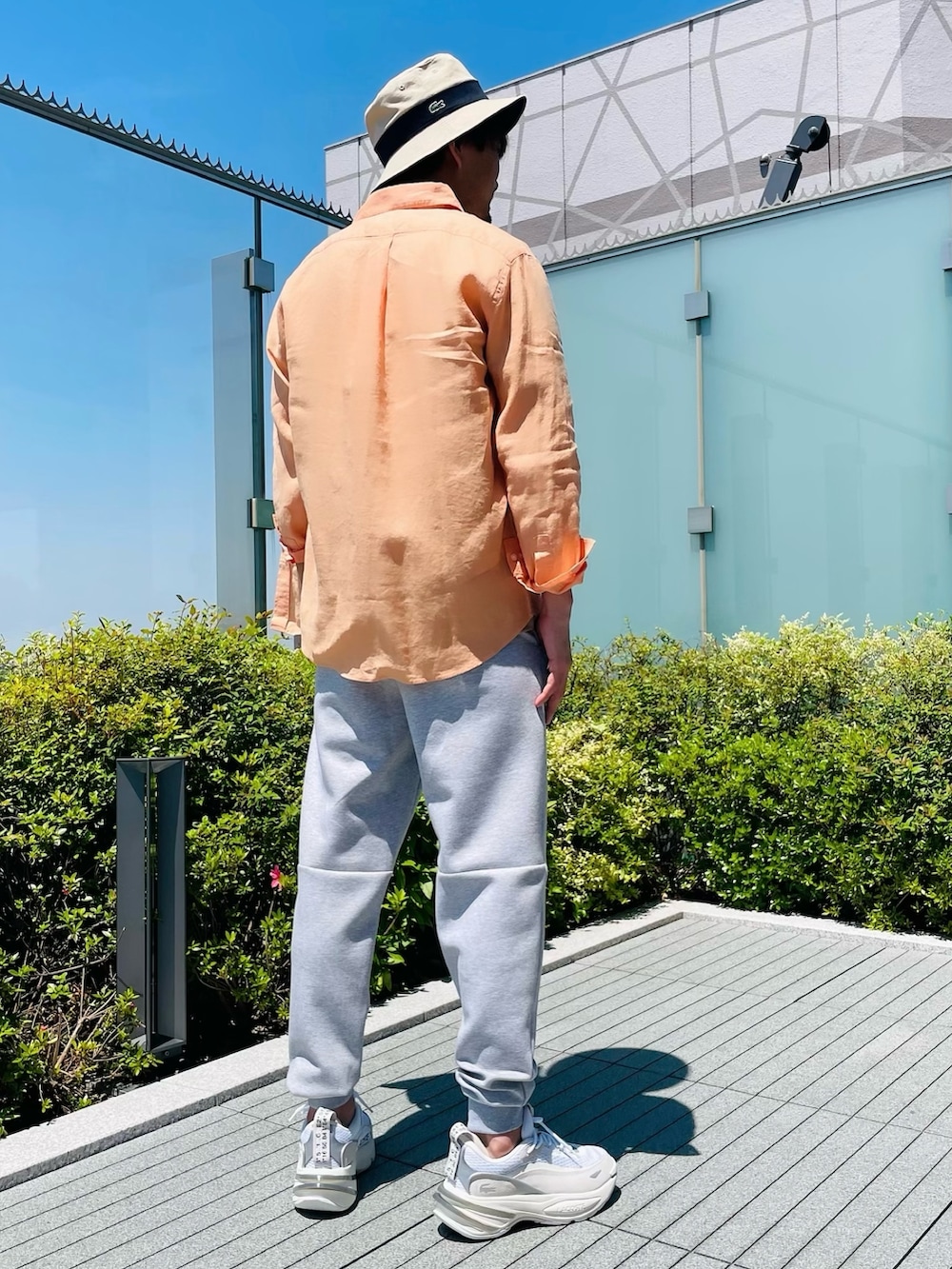 オレンジ系のシャツ/ブラウス、ベージュ系のTシャツ/カットソー、ホワイト系のスニーカーを着用したメンズの夏コーディネートの3枚目の写真