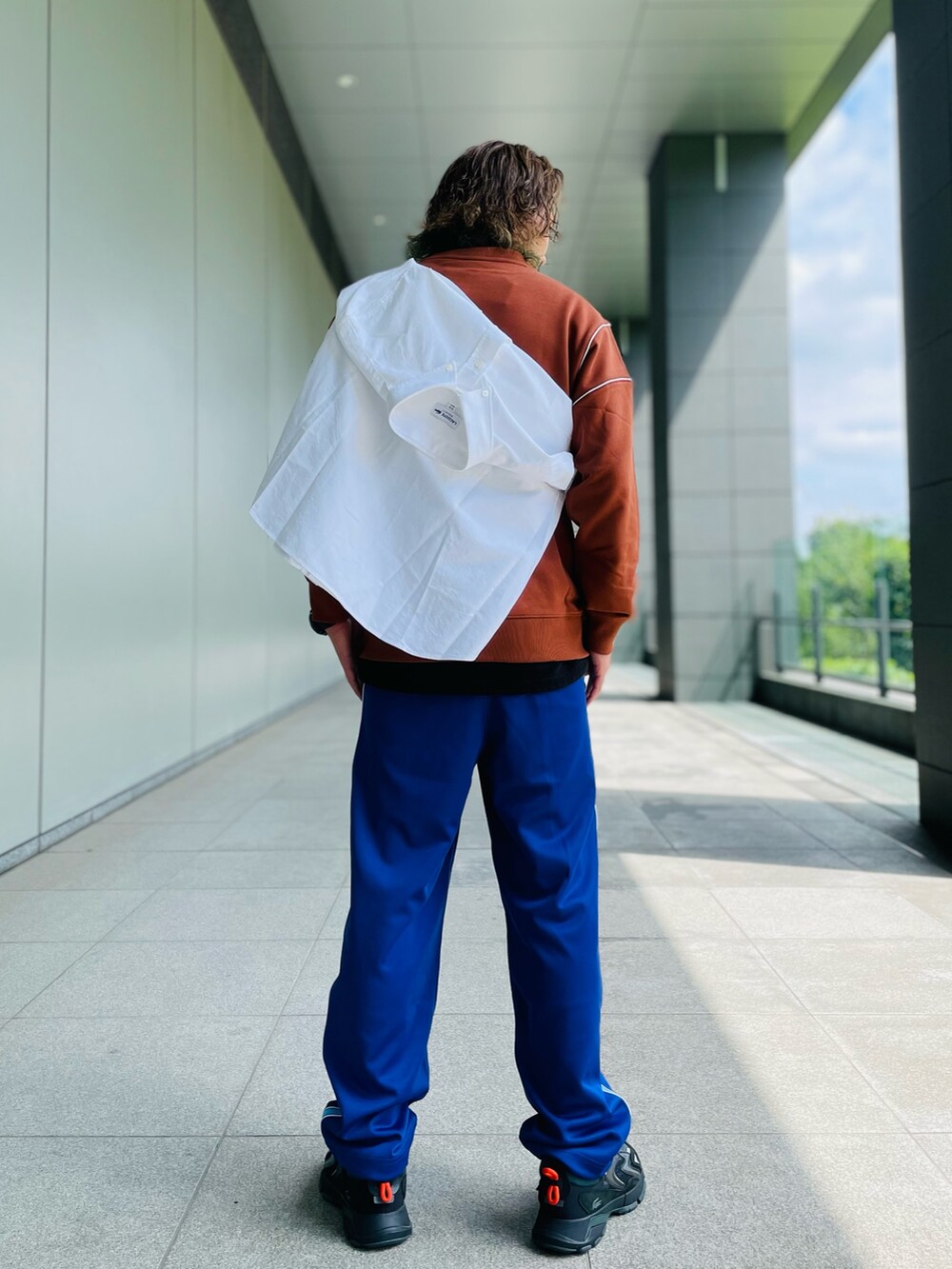 ブラウン系のスウェット、パープル系のチノパンツ、ブラック系のスニーカーを着用したメンズの秋コーディネートの4枚目の写真