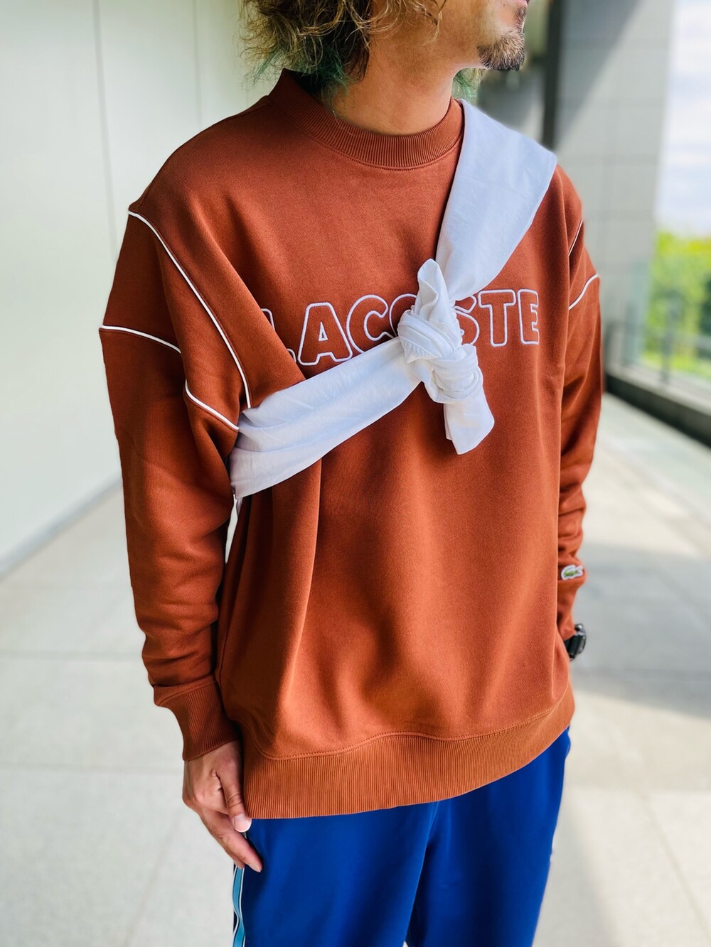 ブラウン系のスウェット、パープル系のチノパンツ、ブラック系のスニーカーを着用したメンズの秋コーディネートの2枚目の写真