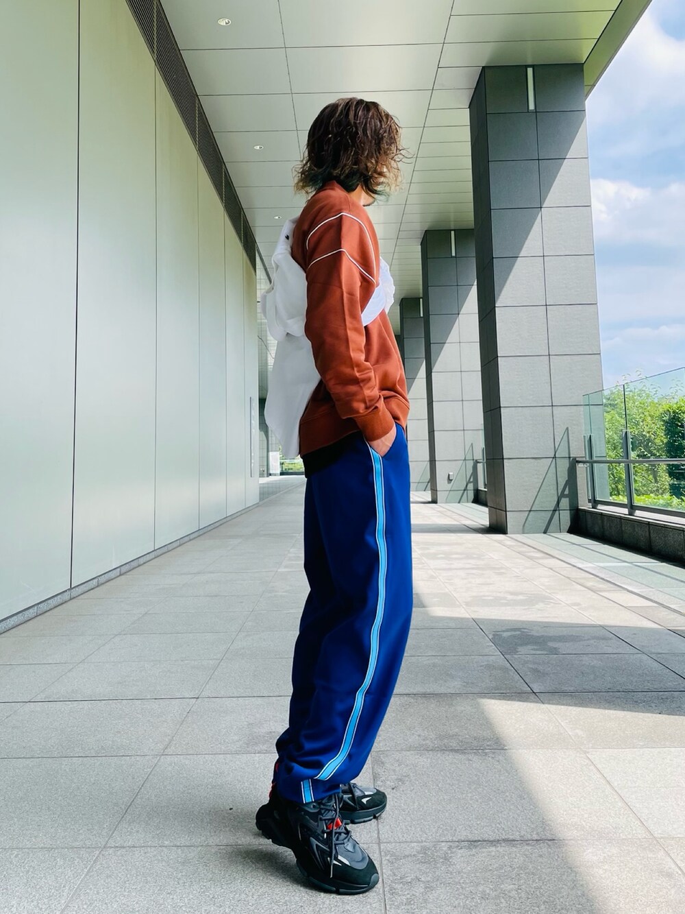 ブラウン系のスウェット、パープル系のチノパンツ、ブラック系のスニーカーを着用したメンズの秋コーディネートの3枚目の写真