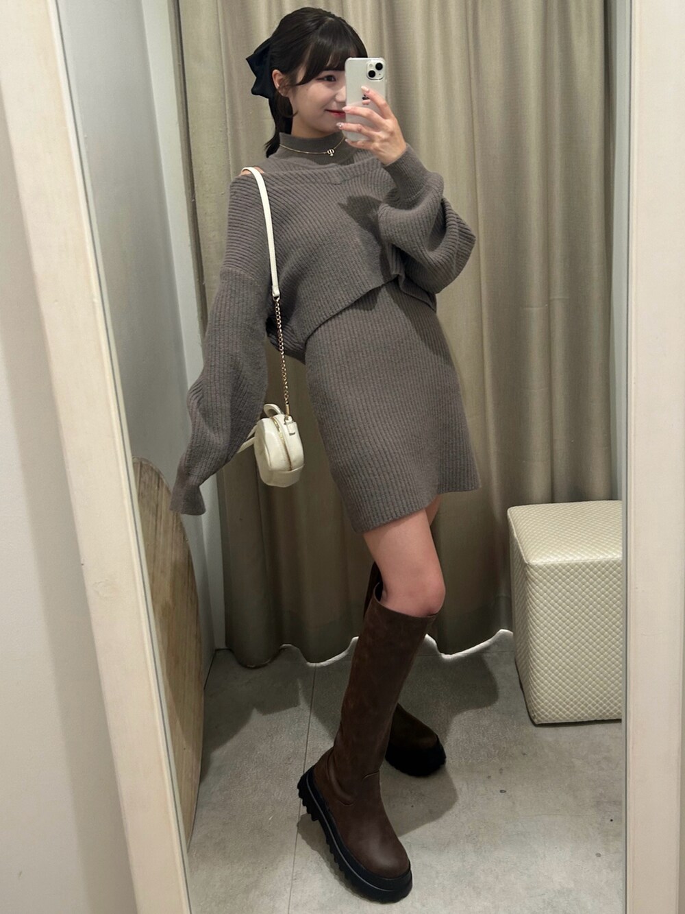 ブラウン系のワンピース、ホワイト系のショルダーバッグ、ブラウン系のブーツを着用したレディースの秋コーディネートの2枚目の写真