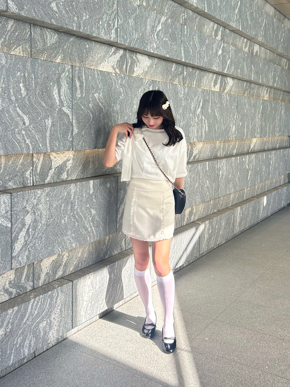 ホワイト系のTシャツ/カットソー、ホワイト系のスカート、ブラック系のショルダーバッグを着用したレディースの春コーディネートの2枚目の写真