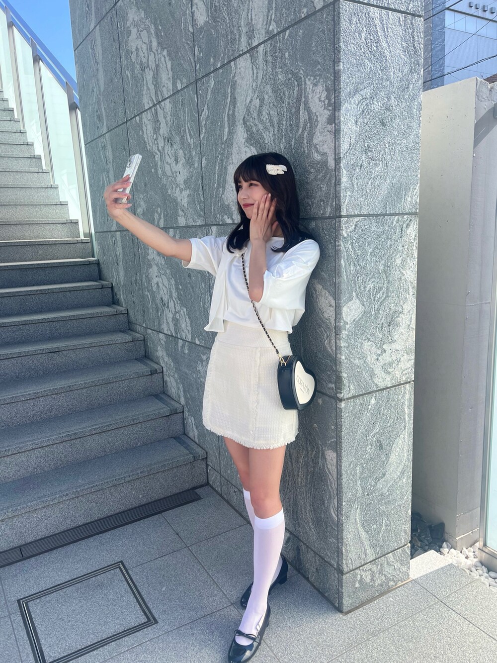 ホワイト系のTシャツ/カットソー、ホワイト系のスカート、ブラック系のショルダーバッグを着用したレディースの春コーディネートの3枚目の写真