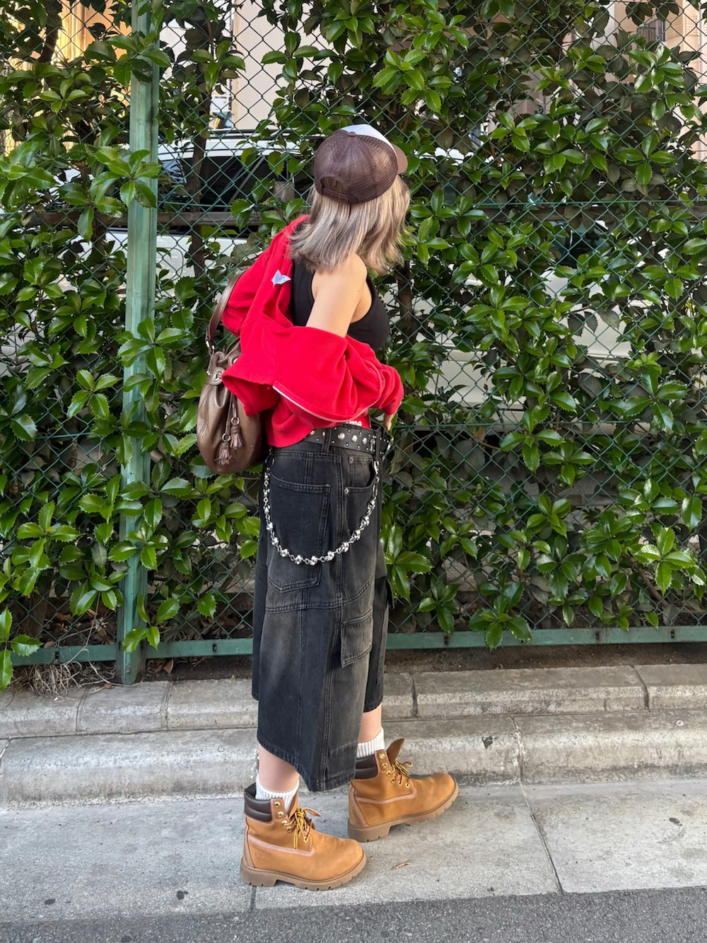 ブラック系のデニムパンツ、ブラウン系のブーツ、ブラック系のベルトを着用したレディースの春コーディネートの2枚目の写真
