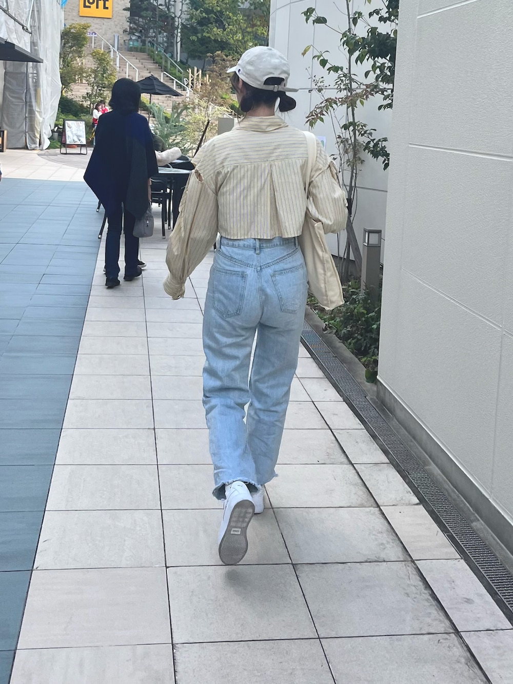 ブルー系のデニムパンツ、イエロー系のシャツ/ブラウス、ホワイト系のスニーカーを着用したレディースの秋コーディネートの2枚目の写真